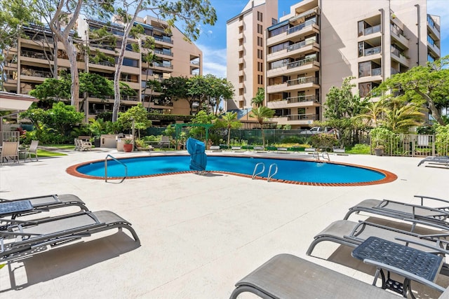 community pool with a patio area and fence