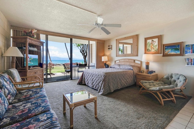 tiled bedroom with access to outside, multiple windows, a textured ceiling, expansive windows, and a ceiling fan
