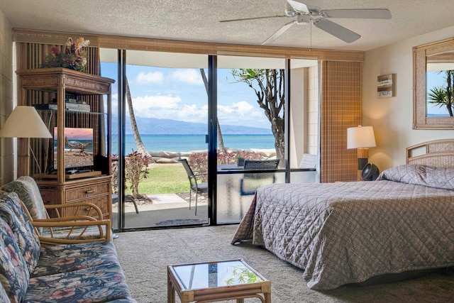 carpeted bedroom featuring a water view, a textured ceiling, ceiling fan, and access to exterior