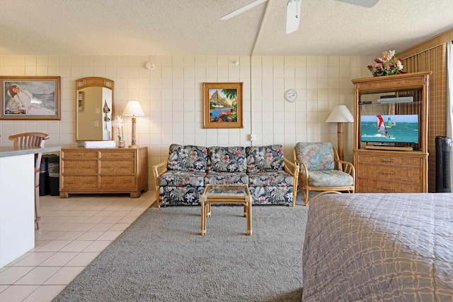 bedroom with a textured ceiling, light tile patterned flooring, tile walls, and ceiling fan