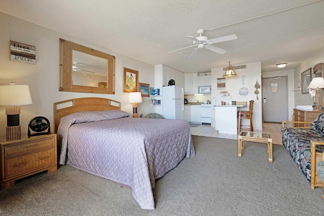 bedroom featuring freestanding refrigerator, light carpet, and a textured ceiling