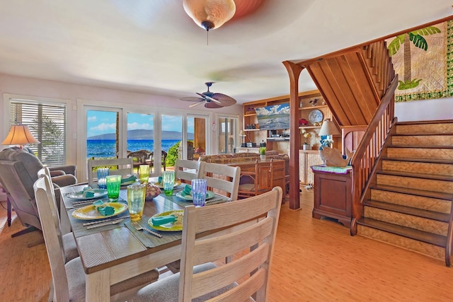 dining space featuring a water view, ceiling fan, stairway, and light wood finished floors