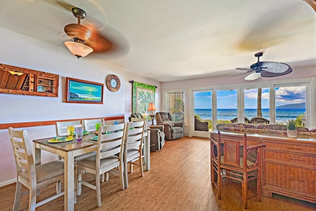 dining area with a water view, ceiling fan, and wood finished floors