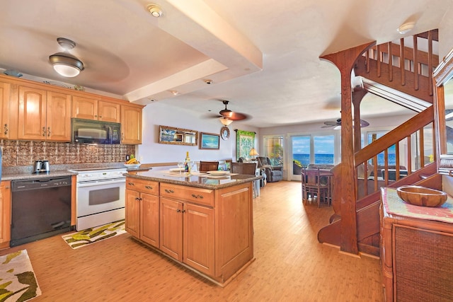 kitchen featuring tasteful backsplash, ceiling fan, a center island, light wood-type flooring, and black appliances