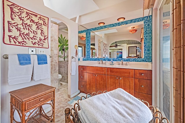 bathroom featuring a sink, tile walls, toilet, and double vanity