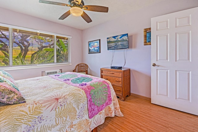 bedroom with light wood-type flooring, ceiling fan, baseboards, and a textured ceiling