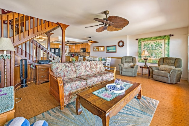 living area with baseboards, stairway, and light wood finished floors