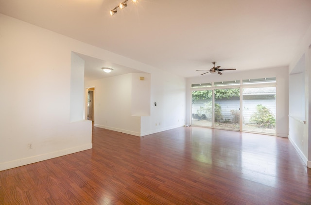 spare room featuring wood finished floors, a ceiling fan, and baseboards