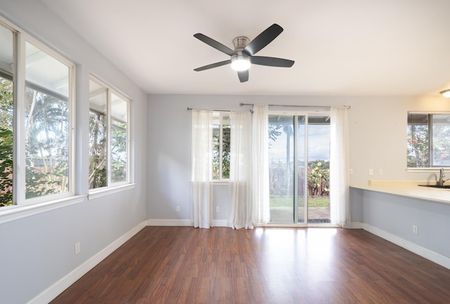 empty room with a sink, a ceiling fan, baseboards, and wood finished floors