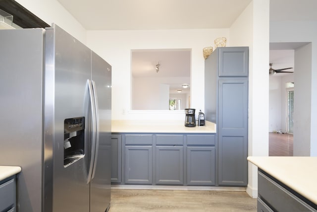 kitchen featuring light wood-type flooring, a healthy amount of sunlight, light countertops, and stainless steel fridge with ice dispenser