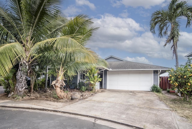 exterior space with a garage, concrete driveway, roof with shingles, and fence