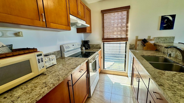 kitchen featuring light tile patterned flooring, sink, light stone counters, and white appliances