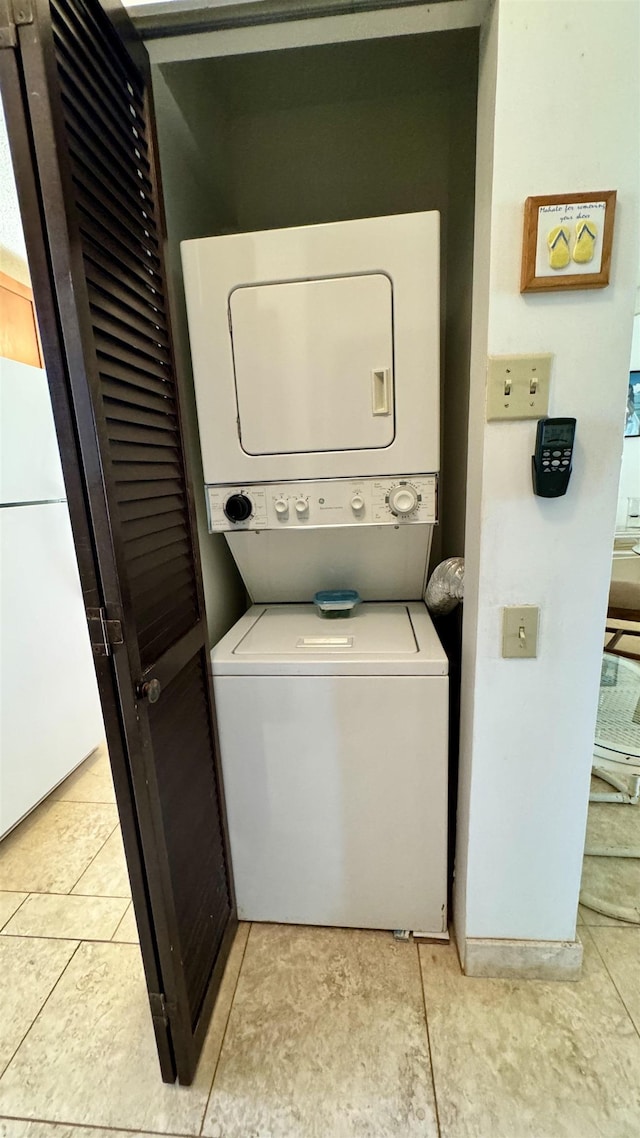 laundry room with stacked washer and dryer, light tile patterned floors, and laundry area