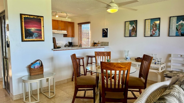 dining space featuring light tile patterned flooring, ceiling fan, rail lighting, and a textured ceiling