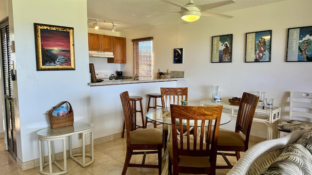 dining room featuring a ceiling fan, light tile patterned flooring, a textured ceiling, track lighting, and baseboards