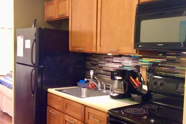 kitchen featuring sink, tasteful backsplash, and black appliances