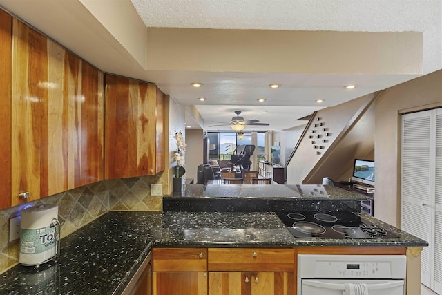 kitchen with a ceiling fan, backsplash, brown cabinetry, white oven, and black electric cooktop