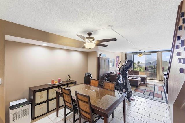 dining space featuring a textured ceiling, a wall of windows, and a ceiling fan