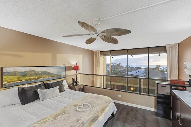 bedroom with ceiling fan, dark wood-type flooring, baseboards, and a textured ceiling