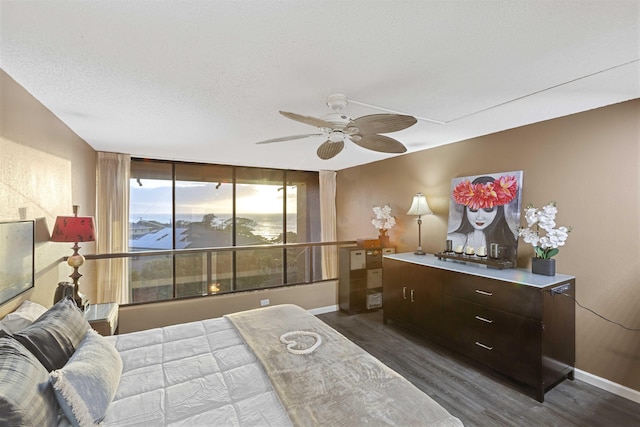 bedroom featuring ceiling fan, baseboards, dark wood-style flooring, and a textured ceiling