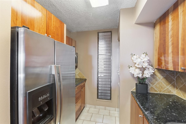 kitchen featuring brown cabinetry, decorative backsplash, stainless steel fridge with ice dispenser, and light tile patterned floors