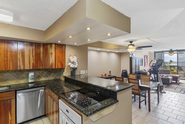 kitchen featuring a peninsula, oven, decorative backsplash, dishwasher, and black electric stovetop