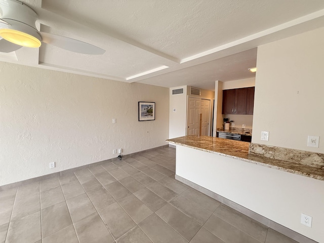 475 Front St Unit 308, Lahaina, HI 96761 - kitchen featuring light stone countertops, baseboards, a textured ceiling, light tile patterned flooring, and dark brown cabinets