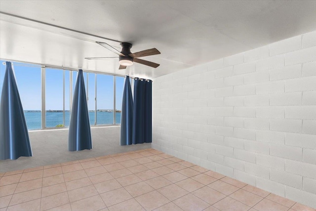 spare room with a textured ceiling, ceiling fan, a water view, and light carpet