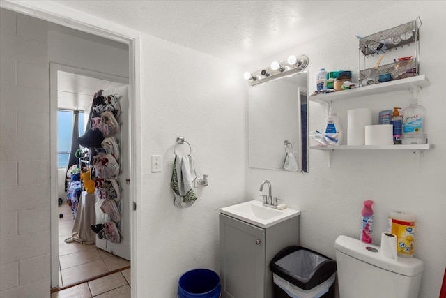 bathroom featuring toilet, vanity, a textured ceiling, and tile patterned floors