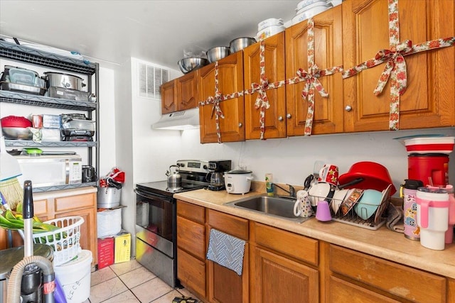 kitchen featuring stainless steel electric stove, light tile patterned floors, and sink