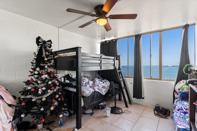 bedroom featuring ceiling fan, a water view, and light tile patterned floors