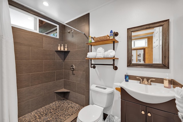 bathroom with vanity, toilet, and a tile shower