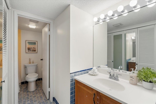 4327 Lower Honoapiilani Rd Unit 801, Lahaina, HI 96761 - bathroom featuring vanity, a closet, a textured ceiling, tile patterned floors, and a wainscoted wall