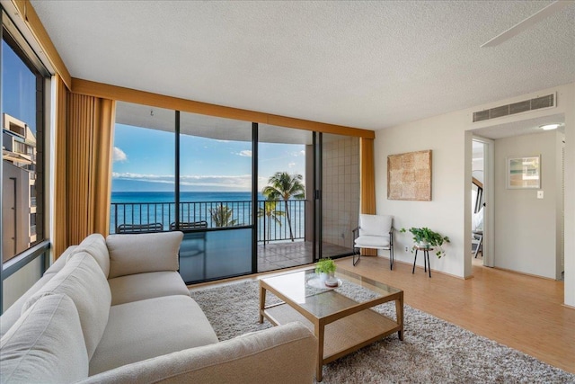 4327 Lower Honoapiilani Rd Unit 801, Lahaina, HI 96761 - living room with a water view, wood finished floors, healthy amount of natural light, a textured ceiling, and expansive windows