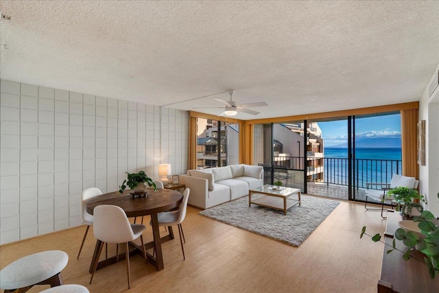 4327 Lower Honoapiilani Rd Unit 801, Lahaina, HI 96761 - living area featuring light wood-type flooring, a textured ceiling, ceiling fan, a water view, and tile walls