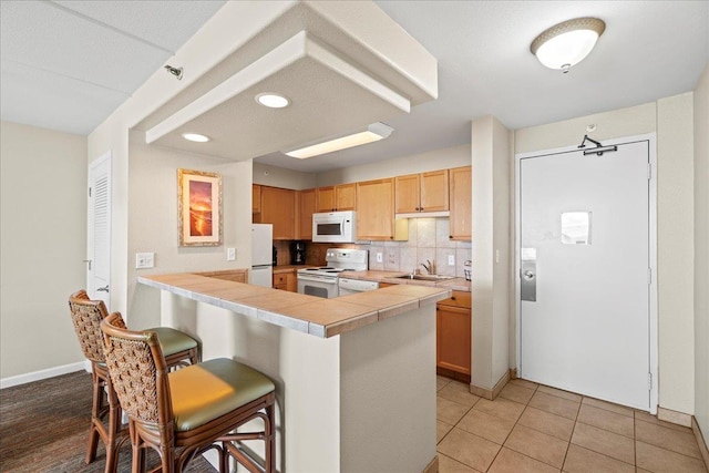 4327 Lower Honoapiilani Rd Unit 802, Lahaina, HI 96761 - kitchen featuring white appliances, a sink, a kitchen bar, backsplash, and a peninsula