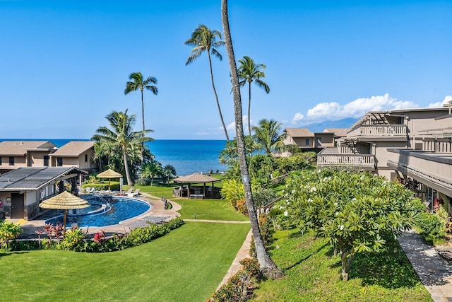 view of pool with a lawn and a water view