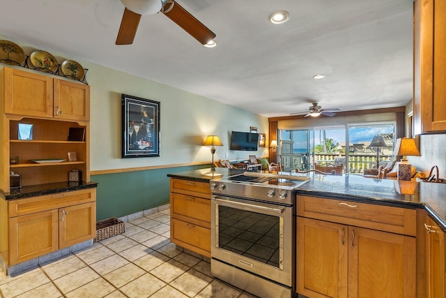 kitchen with stainless steel range, light tile patterned floors, ceiling fan, and dark stone countertops