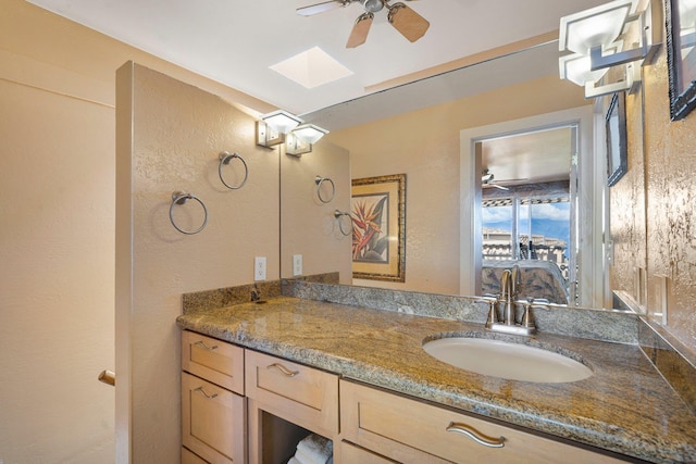 bathroom featuring vanity, a skylight, and ceiling fan