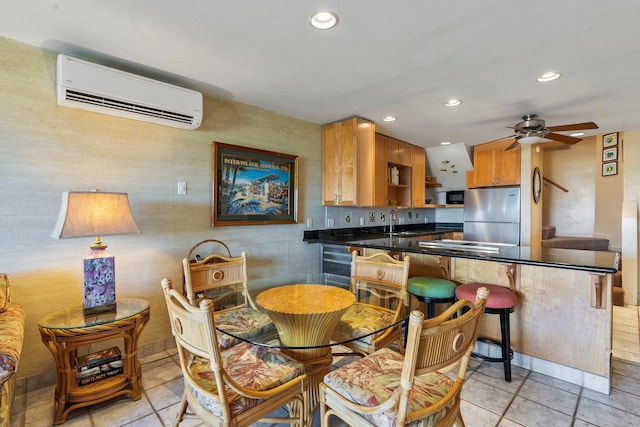 kitchen featuring sink, light tile patterned floors, stainless steel refrigerator, kitchen peninsula, and a wall unit AC