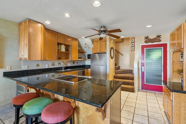 kitchen featuring dark stone counters, a kitchen breakfast bar, sink, kitchen peninsula, and stainless steel appliances