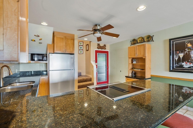 kitchen featuring stainless steel refrigerator, ceiling fan, sink, cooktop, and kitchen peninsula