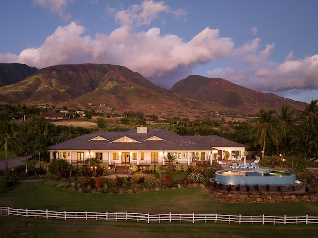 back house at dusk featuring a mountain view and a yard