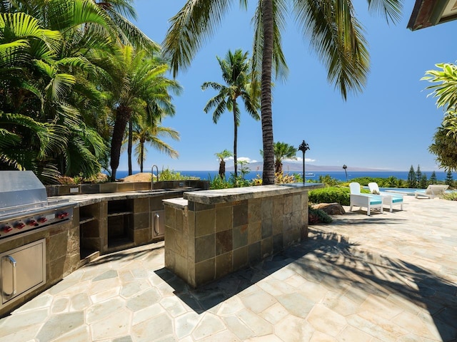 view of patio with sink, an outdoor kitchen, area for grilling, a swimming pool, and a water view