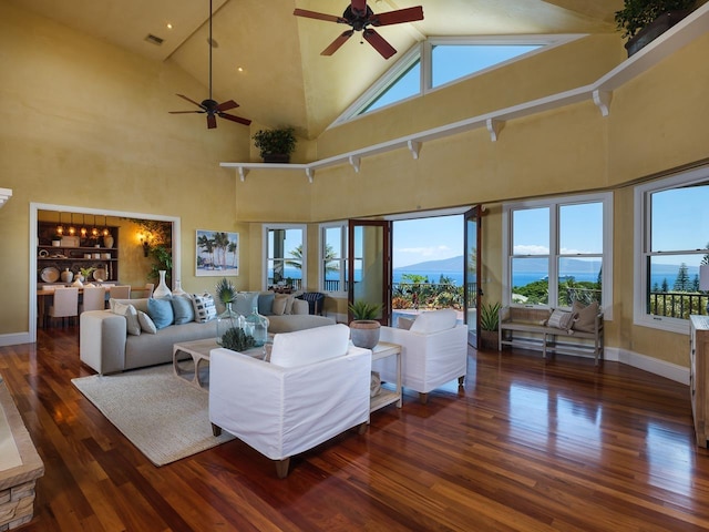 living room featuring ceiling fan, dark hardwood / wood-style floors, and a towering ceiling