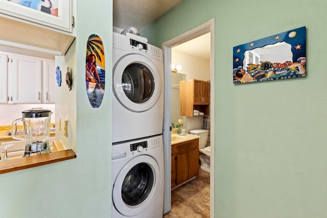 laundry room with a textured ceiling and stacked washer / dryer