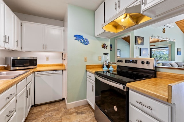 kitchen with light tile patterned floors, appliances with stainless steel finishes, sink, and white cabinetry