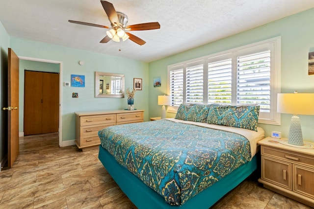 bedroom featuring multiple windows, ceiling fan, and a textured ceiling