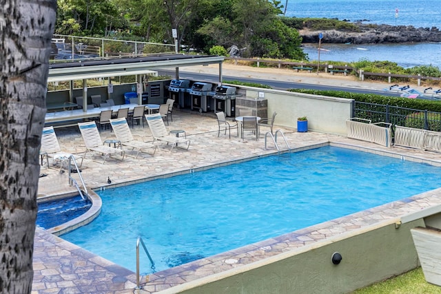 view of pool with a patio, a grill, and a water view