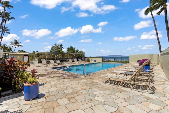 view of swimming pool featuring a patio and a water view